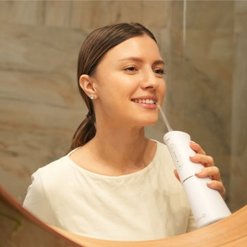 Femeie care utilizeaza irigator bucal luvlu